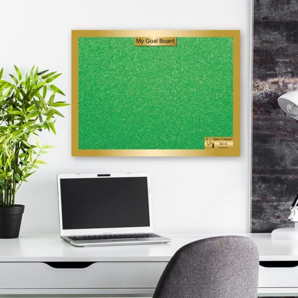 A green bulletin board hanging on the wall above a desk.