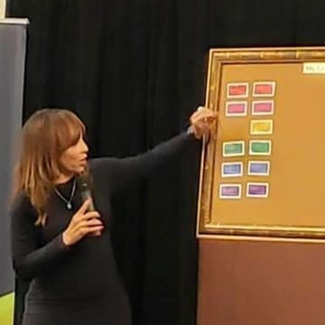 A woman pointing to a board with many different colored labels.